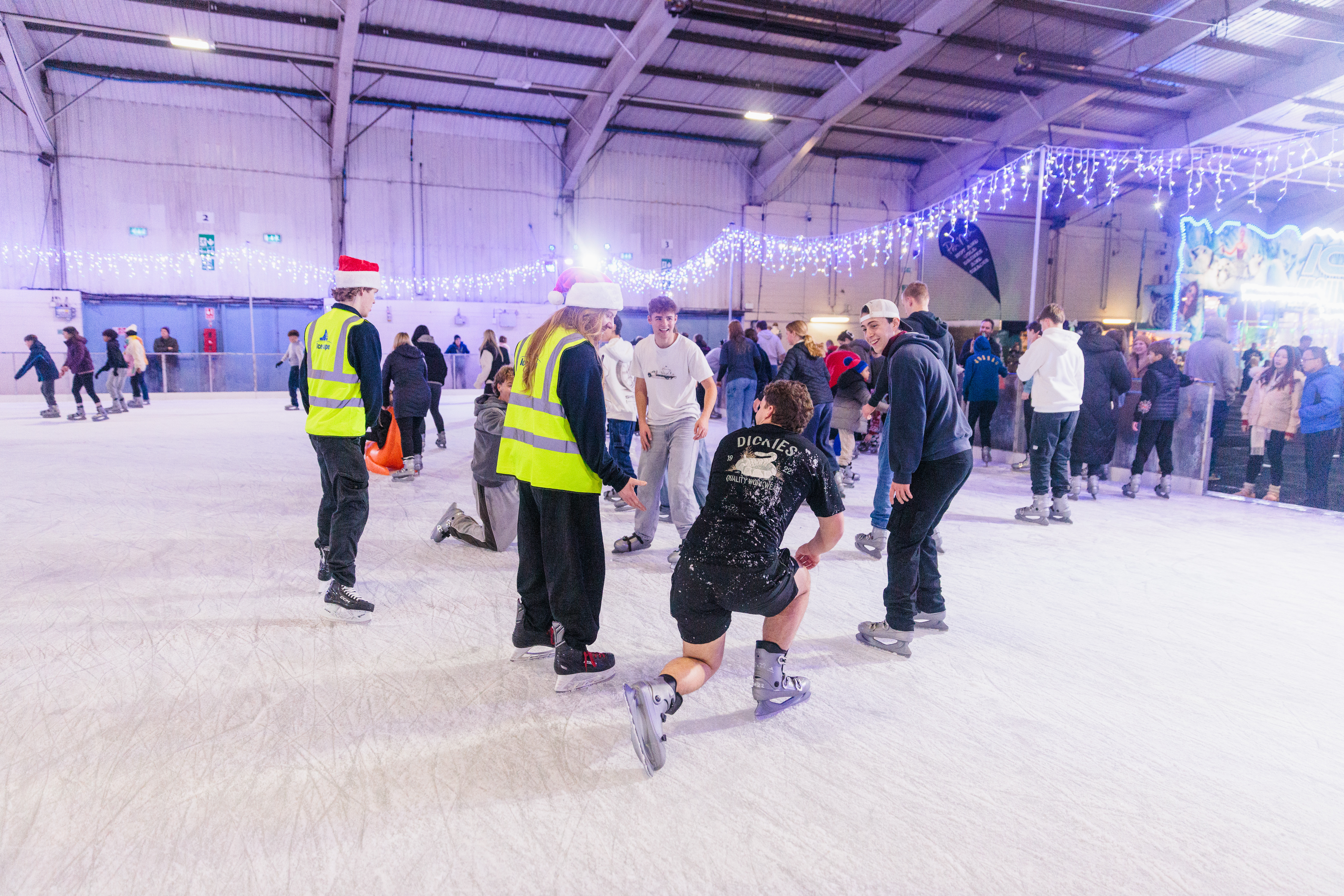 Icescape staff on a winter ice rink helping a customer on the ice. 