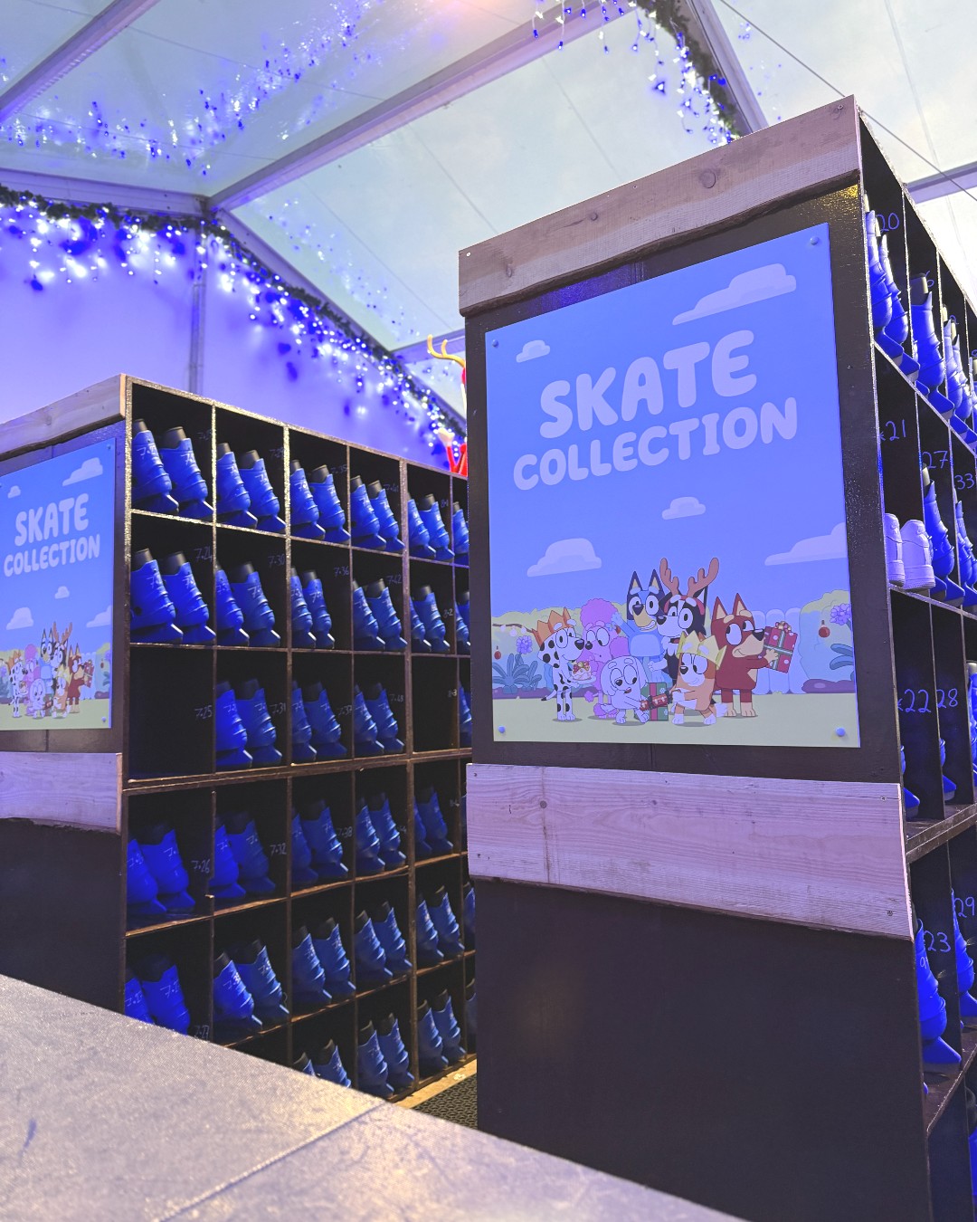 Racks of blue ice skates with a Bluey Signage of Bluey and friends showing Skate Collection. 