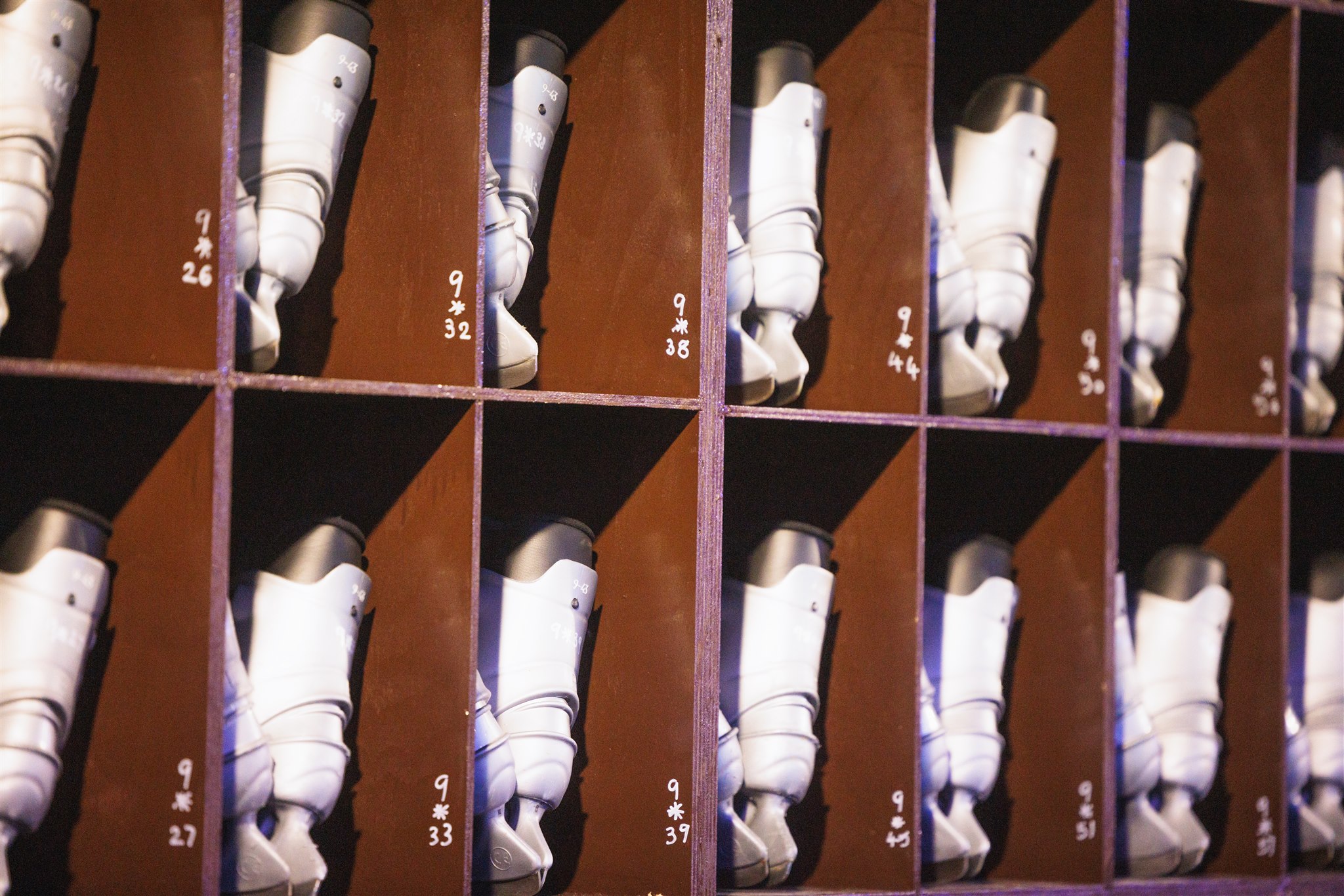 Grey ice skates, neatly placed in racks ready to be used for ice skating. 